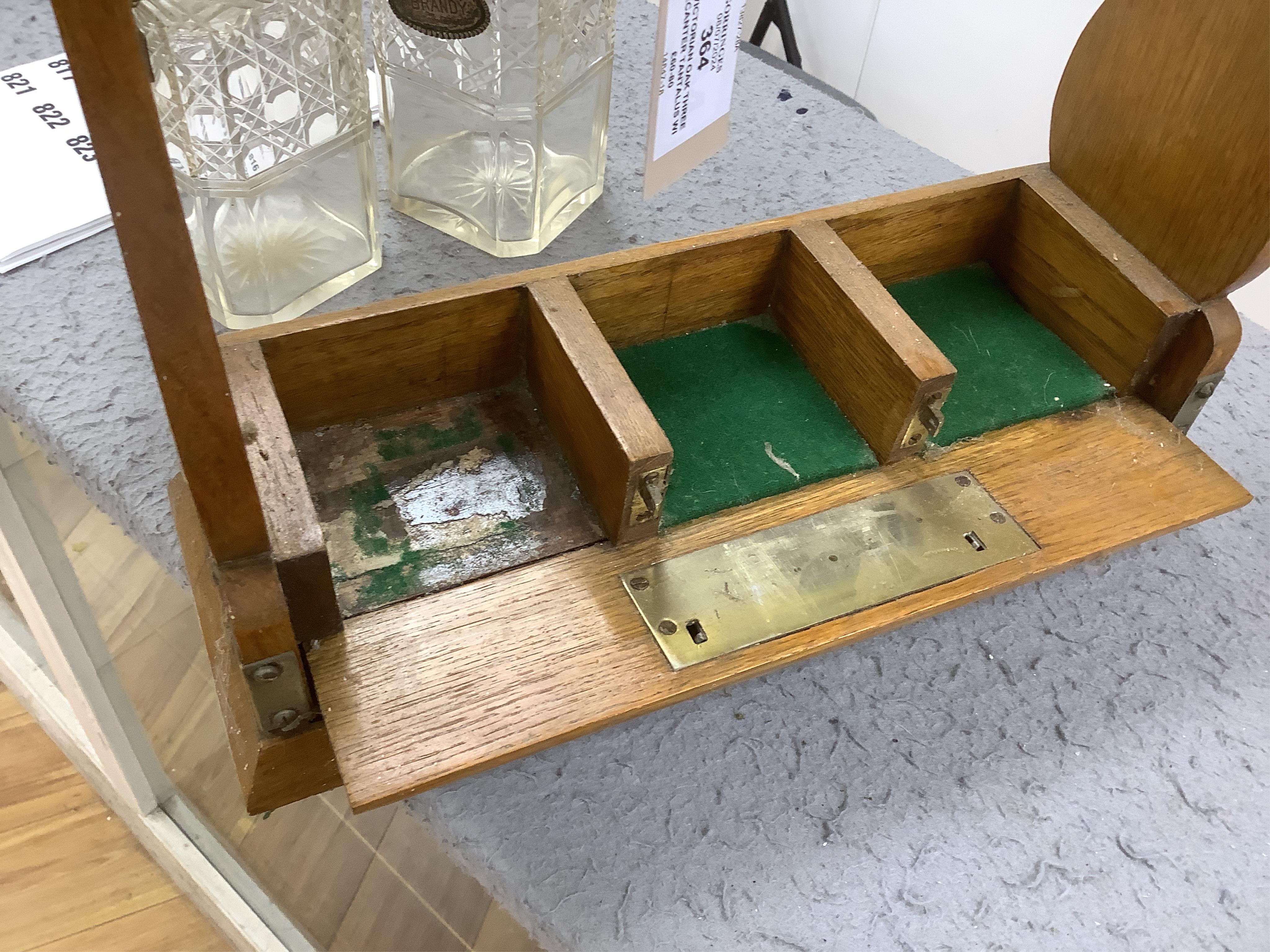 A Victorian oak three decanter tantalus with four spirit labels, and key, 37cm wide. Condition -fair